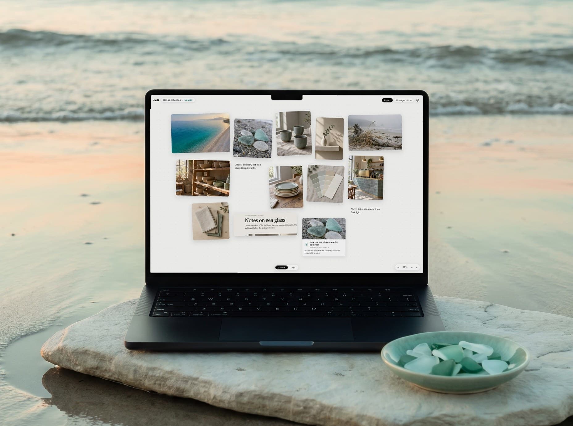 A MacBook on a pale stone at the water's edge, a celadon dish of sea glass beside it. On screen, a Drift board: a spring moodboard of sea, glazes, linen and a kiln room.