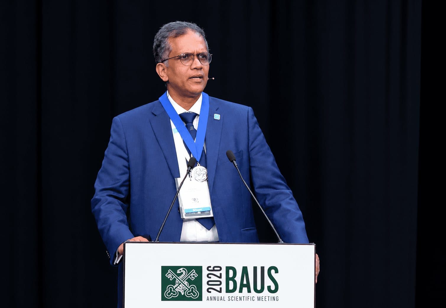 Joe Philip giving the presidential address at the BAUS 2026 Annual Scientific Meeting, wearing the presidential chain