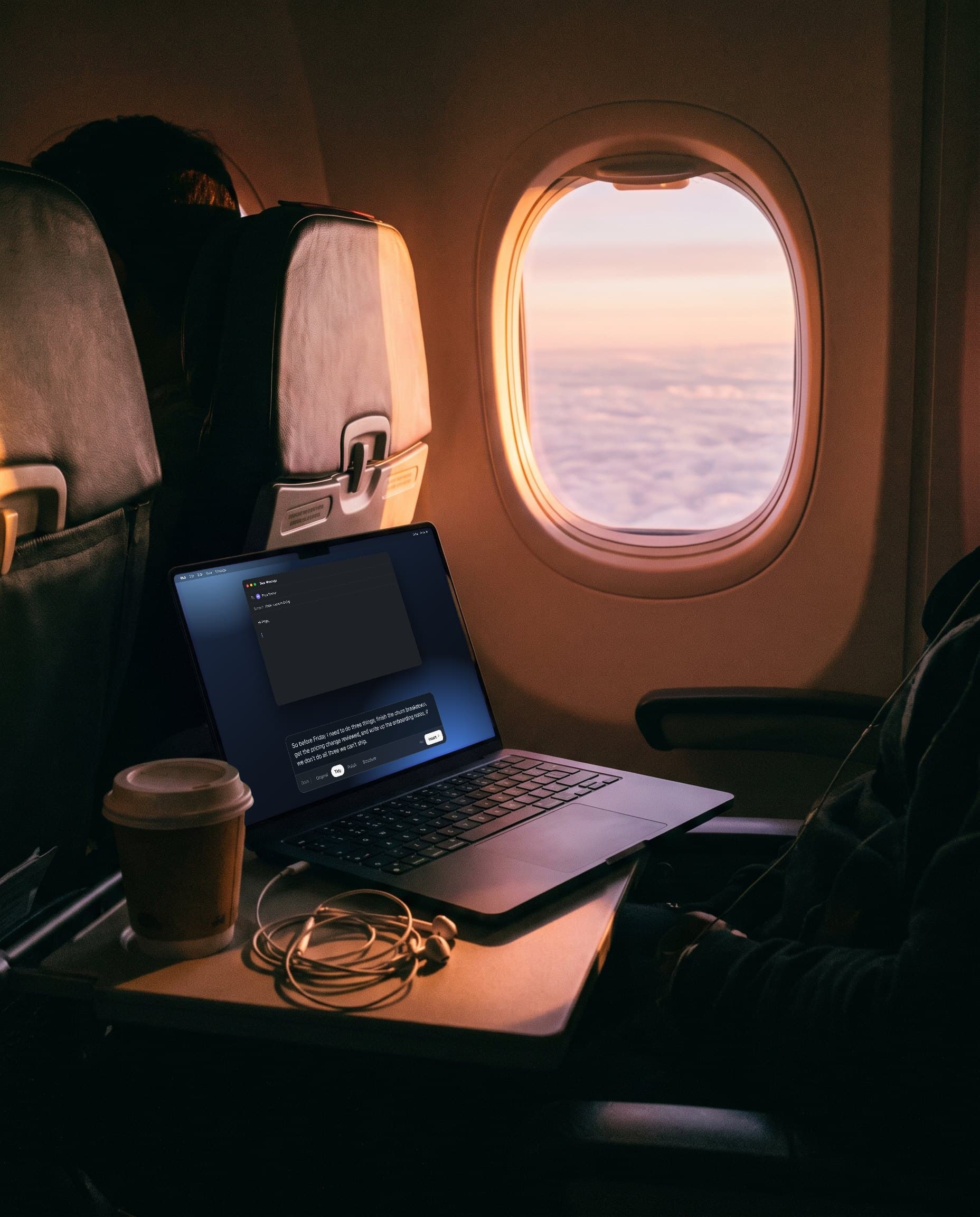 A MacBook on a plane tray table at sunrise, the Tidy version on screen